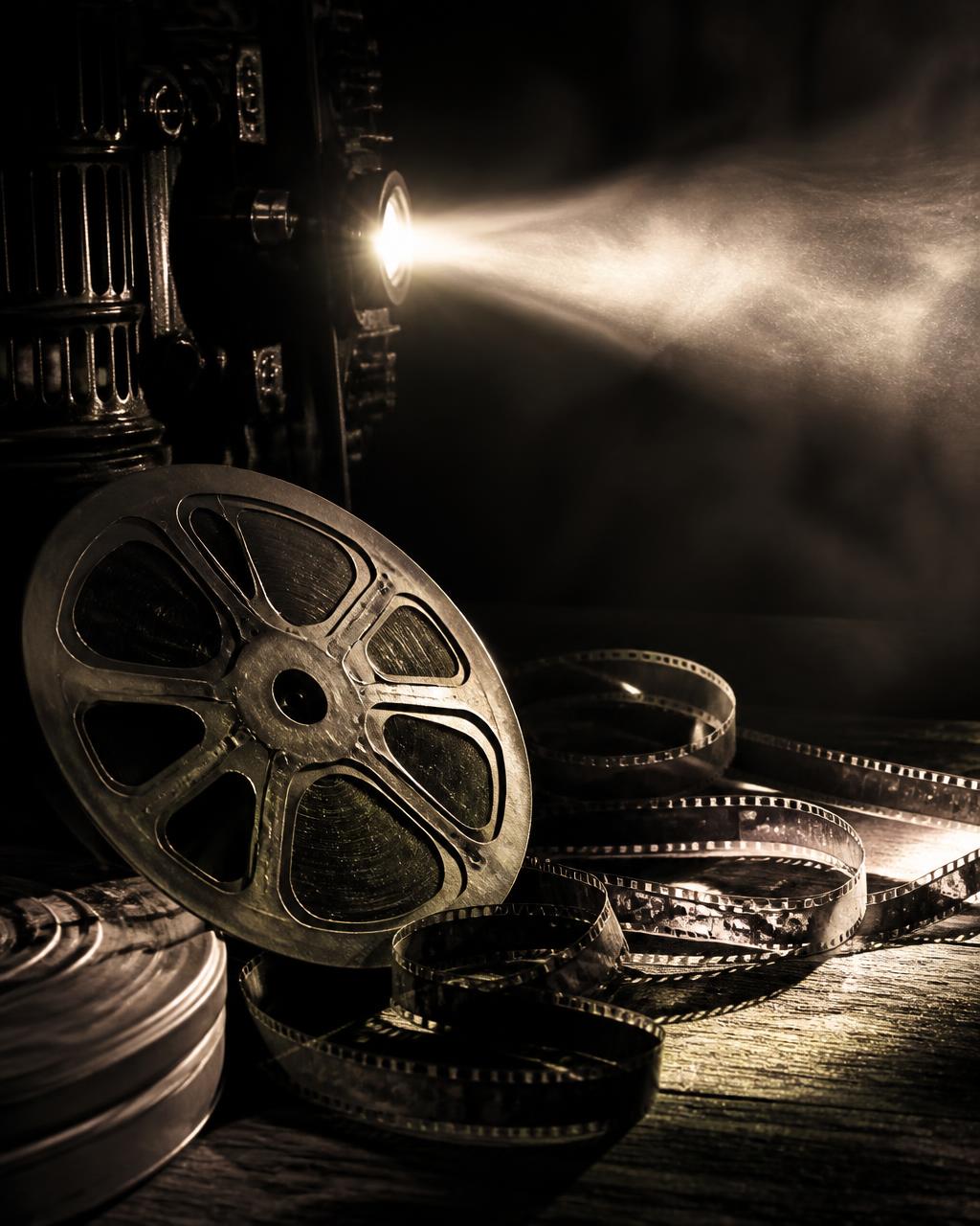 Vintage 35mm film reel and film strips lit by a projector beam